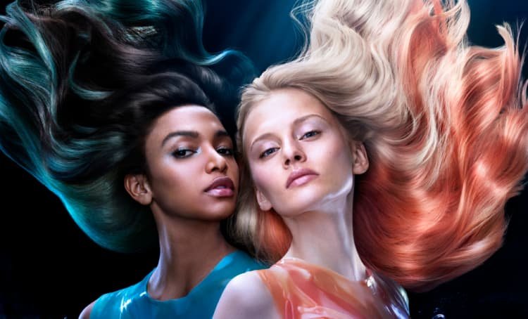 Two women posing, one with blonde and orange peekaboo hair, the other with dark hair and vivid blue peekaboo highlights